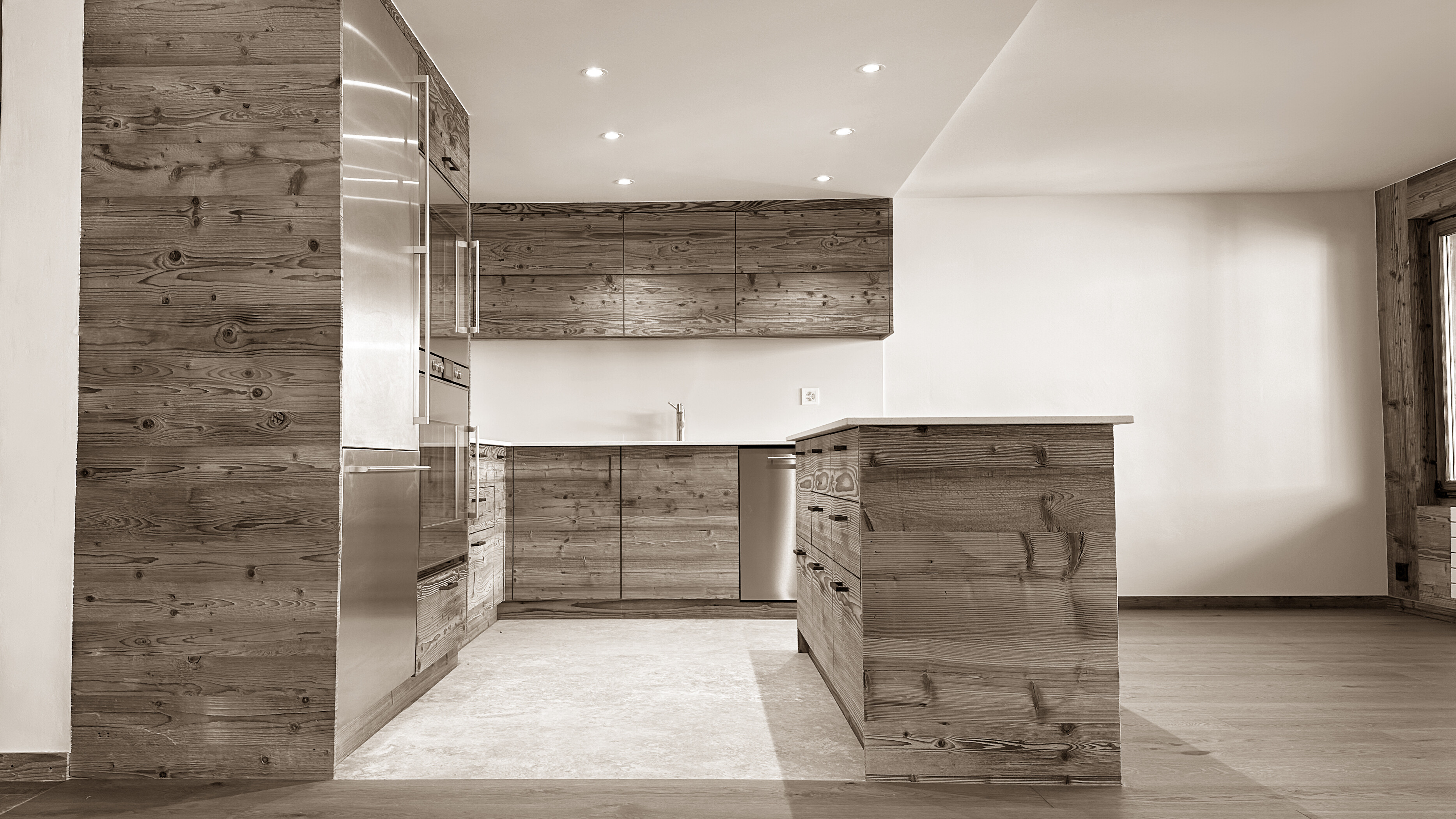 Spacious and modern kitchen blending rustic wooden cabinetry with sleek stainless-steel appliances, featuring a central island for both cooking and gathering, all bathed in soft, warm lighting that enhances its inviting atmosphere.