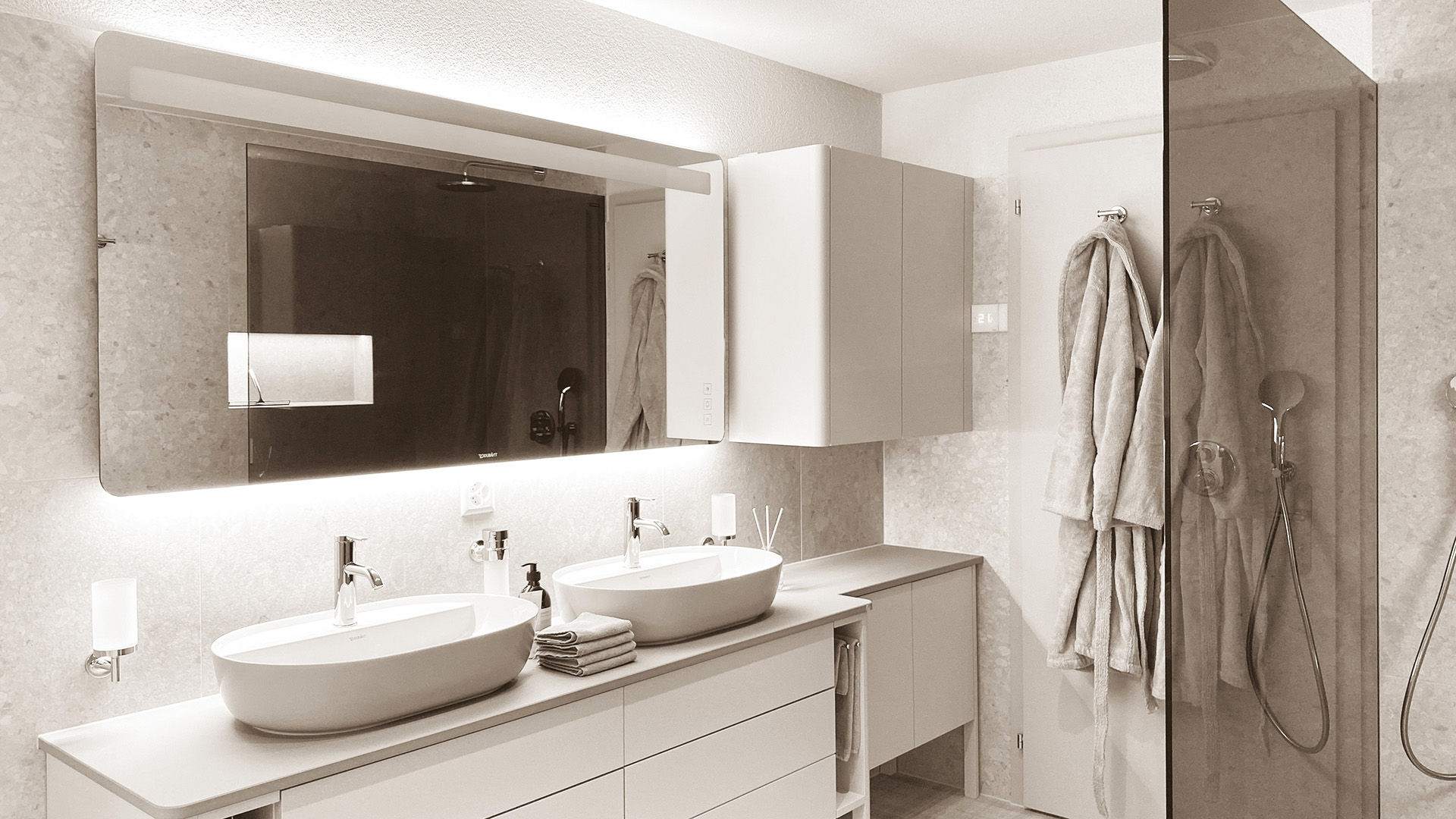 Spacious bathroom featuring two elegant sinks with modern fixtures, set against a stylish backdrop of sleek tiles and contemporary design, offering a functional and luxurious space.