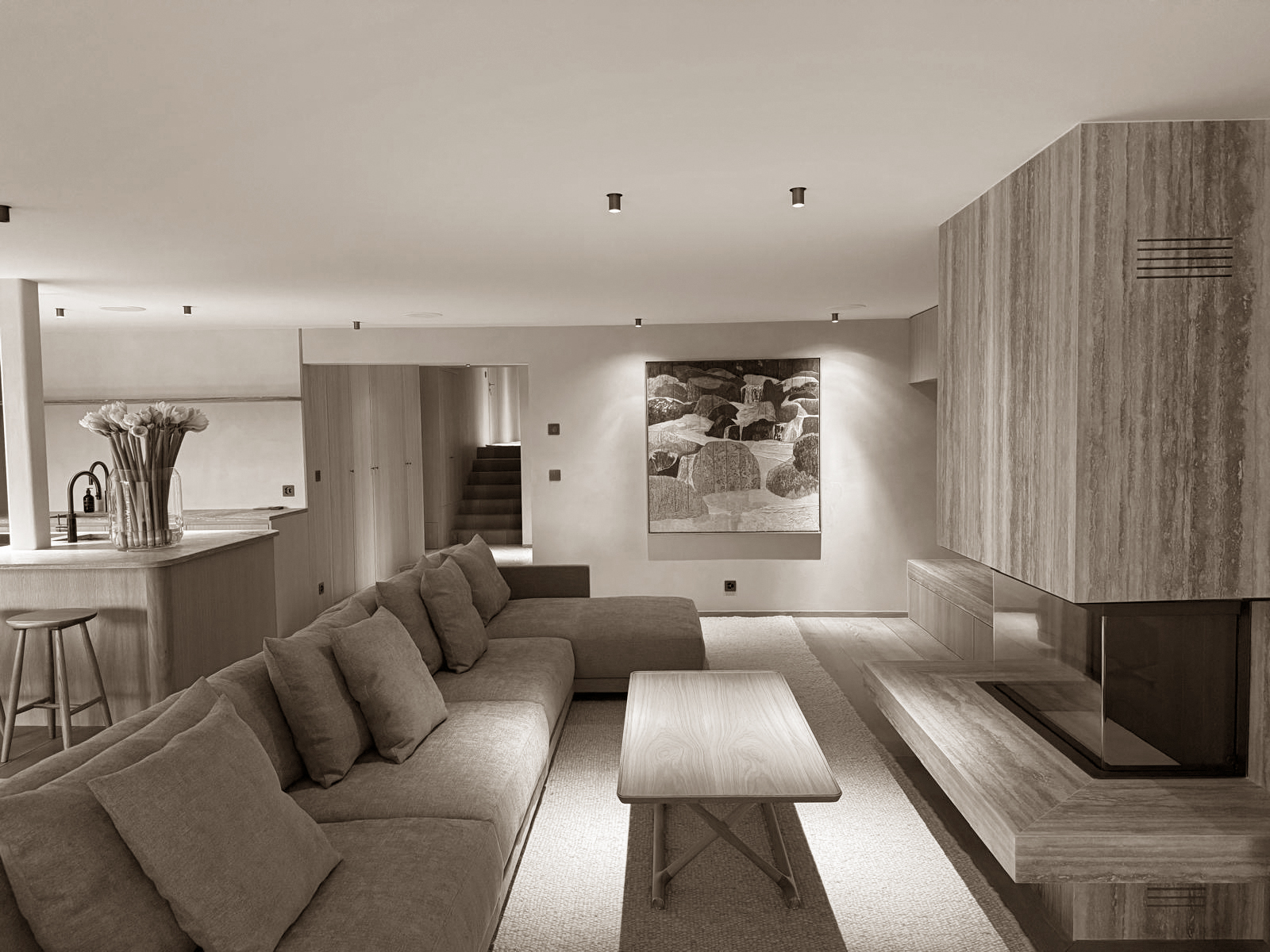 A serene open-plan living area with a textured stone fireplace, soft-toned sofa, and elegant built-in cabinetry. Subtle lighting and natural materials offer a warm, balanced ambiance.