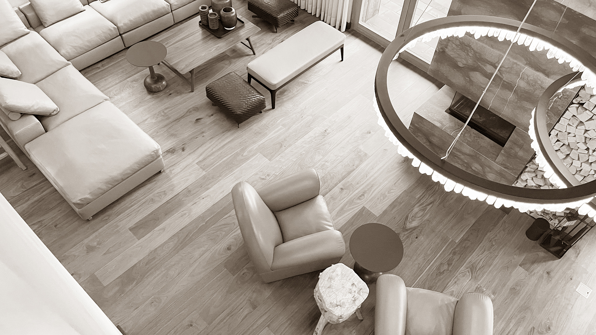 Top-down view of the living room in Chalet Harmony, featuring luxurious leather armchairs and sofa, modern lighting, and a sleek contemporary fireplace, creating an elegant and inviting space.