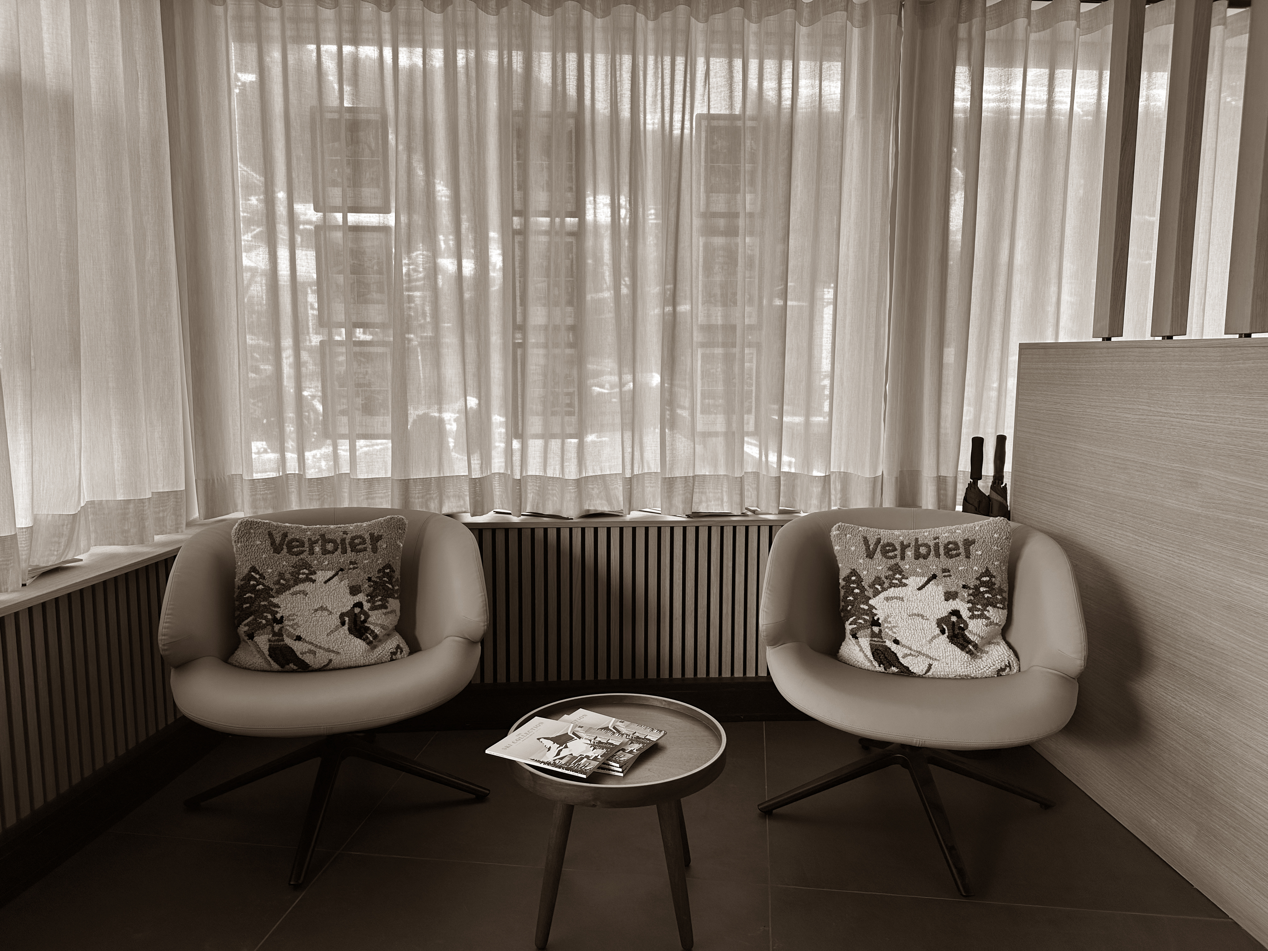 A cozy corner with retro-style armchairs and Verbier-themed pillows invites guests to relax in warmth and charm.