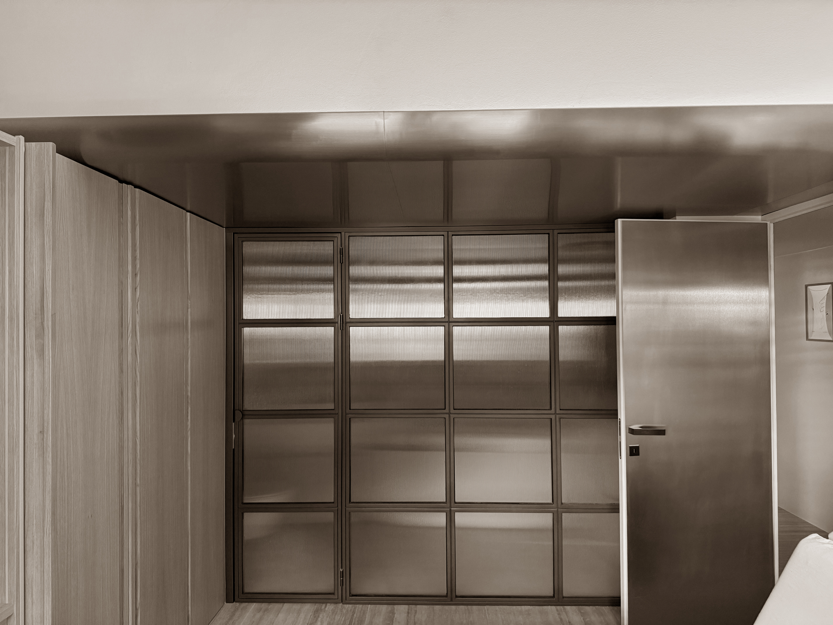 Refined architectural feature wall composed of translucent panels framed in dark metal, offering a subtle play of light and texture. Paired with sleek wood and brushed metal surfaces, the space embodies a clean, modern elegance with a discreet industrial edge. Refined architectural feature wall composed of translucent panels framed in dark metal, offering a subtle play of light and texture. Paired with sleek wood and brushed metal surfaces, the space embodies a clean, modern elegance with a discreet industrial edge.