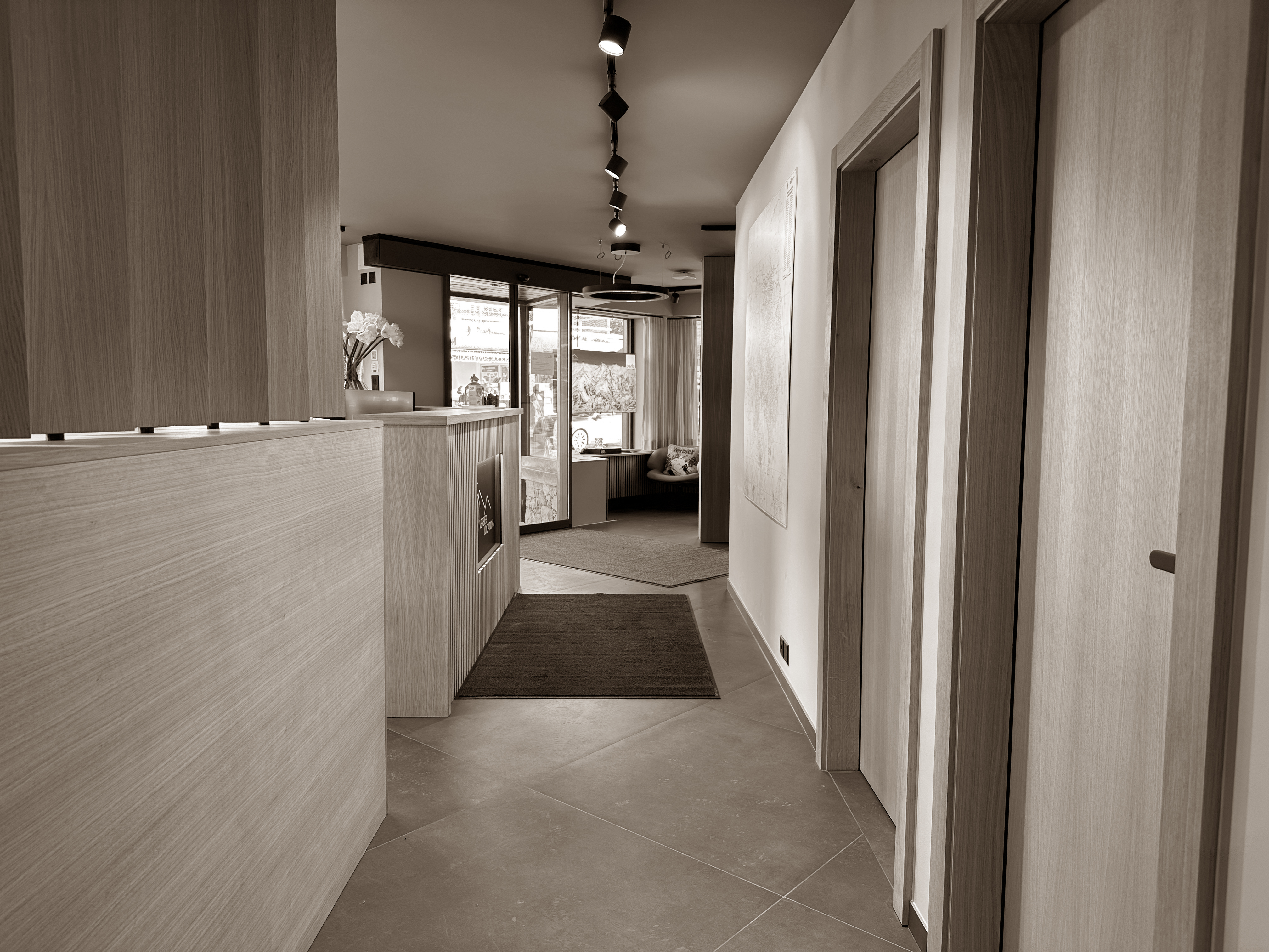 A clean, geometric corridor leads to an inviting space, where natural wood tones and modern lighting balance professionalism with warmth.