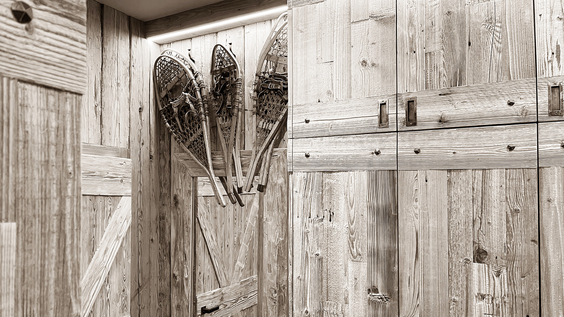 Close-up of wooden walls adorned with vintage snowshoes, highlighting the rustic charm and traditional alpine elements that bring warmth and character to the interior design.